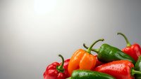 Fresh colorful hot chili peppers with water drops on neutral background for culinary and cooking projects.