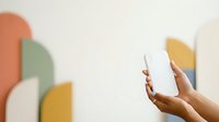 Woman holding smartphone with colorful abstract shapes in background, modern mobile technology and communication concept for web and app design projects.