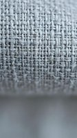 Gray linen fabric texture with detailed weave pattern showing natural fiber threads in close-up macro photography for textile and material design projects.