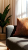 Modern gray sofa with geometric patterned cushion in sunlit living room with houseplant and curtains for interior design and home decor concepts.
