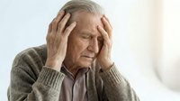 Senior Caucasian man experiencing headache holding head with both hands showing pain and stress in healthcare concept for medical advertising.