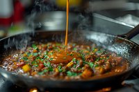 Steaming hot curry sauce being poured into pan with meat and vegetables, garnished with fresh herbs. Steam rising creates atmospheric cooking scene.