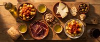 Mediterranean appetizer spread with olives, cheese, nuts, and olive oil on rustic wooden table for entertaining and social dining occasions.
