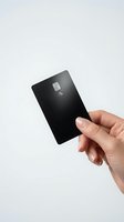 Hand holding black credit card with chip and contactless payment symbol on white background for financial services and banking concepts.