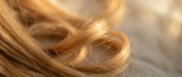 Soft golden blonde hair strands with natural shine and movement, close-up macro photography showing texture and highlights for beauty and haircare concepts.