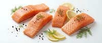 Fresh salmon fillets with dill and lemon slices on white background, raw fish portions seasoned with black pepper, healthy seafood for cooking.