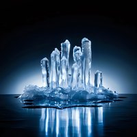 Glowing ice crystal formation with vertical spires creating dramatic reflections on dark surface against blue gradient background.