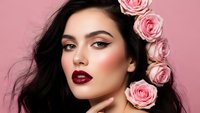 Young woman with dark hair and burgundy lipstick adorned with pink roses against soft pink background for beauty and fashion concepts.