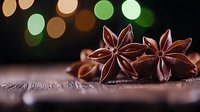 Star anise pods on rustic wooden surface with soft bokeh lights in background creating magical holiday atmosphere for seasonal cooking and decoration.