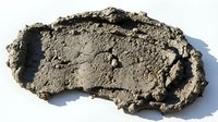 Wet sand or clay molded into organic shape on white background, suitable for construction, geology, material texture, and educational content.