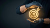 Hands in black gloves holding a glowing golden target with arrow icon, symbolizing business goals, strategy, and achievement on dark background.