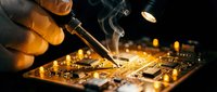 Technician repairing electronic circuit board with soldering iron in workshop. Professional electronics repair service and microchip technology maintenance work.