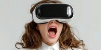 Young woman with open mouth wearing virtual reality headset against neutral background, expressing excitement during immersive digital experience.