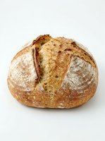 Artisan sourdough loaf with deep scoring and crispy golden crust, isolated on white background for bakery, food, and culinary design projects.