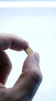 Close-up of hand holding tiny SIM card against white background. Isolated shot showing small mobile communication chip for smartphone connectivity and wireless network setup.