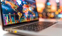 Laptop screen displaying global financial data visualization with colorful world map and market charts on blurred bokeh background, modern business analytics concept.