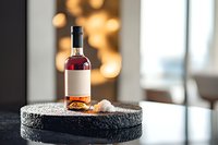 Elegant rose wine bottle on black stone surface with bokeh lights background, styled product photography for restaurant menu and beverage marketing.