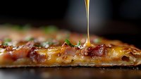 Melted cheese and crispy bacon on pizza slice with dripping honey or maple syrup, garnished with fresh herbs, extreme close up macro food photography.