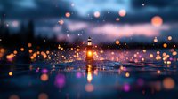 Glowing orange and purple bokeh lights reflecting on water surface at dusk with soft focus raindrops creating magical atmospheric mood. Suitable for background designs.