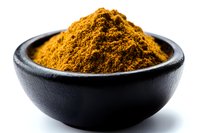 Ground turmeric powder heap in black ceramic bowl on white background. Bright yellow-orange aromatic spice used in Asian cuisine and natural medicine.
