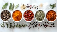 Colorful aromatic spices and herbs in white ceramic bowls on light background with scattered peppercorns, dried chili flakes and fresh sage leaves.