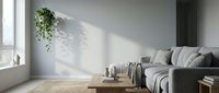 Minimalist living room with gray sofa, wooden table, hanging plant, and natural sunlight casting shadows on white wall for interior design projects.