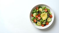 Fresh mixed green salad with avocado, cherry tomatoes and cucumber in white bowl on clean background for healthy eating and nutrition concepts.