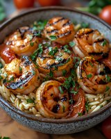 Grilled jumbo shrimp with charred marks served over orzo pasta, garnished with fresh herbs and cherry tomatoes in rustic ceramic bowl. Fresh seafood dinner.