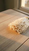 Dried wheat bundle resting on wooden table near window with natural sunlight, suitable for rustic home decor, agricultural themes, and harvest-inspired designs.