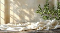 Soft white fabric with gentle folds on wooden surface in natural morning sunlight with olive branch, perfect for lifestyle, wellness, and minimalist design backgrounds.
