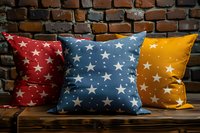 Decorative throw pillows with star pattern in red, blue and yellow colors arranged on wooden bench against rustic brick wall background, perfect for home decor and interior design projects.