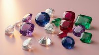 Collection of colorful precious gemstones including emerald, ruby, sapphire and amethyst stones scattered on pink surface for jewelry making and luxury design.