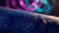 Sparkling blue glitter surface with colorful bokeh lights creating magical atmosphere for party celebrations and festive events.