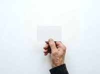 Mature adult male hand holding blank white card against neutral background, suitable for business messaging, promotional content, and marketing materials.