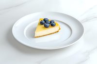 Slice of creamy cheesecake topped with fresh blueberries served on white plate against marble background, food photography for restaurant menus and blogs.
