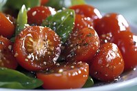 Roasted cherry tomatoes with herbs and olive oil in white bowl, caramelized vegetables for Mediterranean cuisine and healthy cooking recipes.