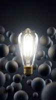 Glowing vintage Edison bulb with warm filament surrounded by blurred spheres on dark background, representing innovation, creativity, and unique ideas for design and marketing projects.