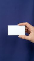 Woman's hand holding a blank white business card against a deep blue background, mockup for branding and corporate identity design.