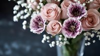 Elegant floral arrangement featuring soft pink roses, purple gerberas, and white baby's breath in a glass vase for weddings, events, and home decor.