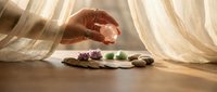 Hands performing crystal healing therapy with colorful gemstones on wooden surface in soft natural light for wellness and spiritual practices.