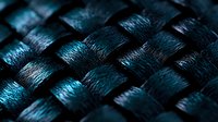 Interwoven dark blue carbon fiber material in macro view showing detailed texture pattern and metallic sheen, suitable for technology and industrial design backgrounds.