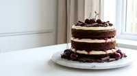 Chocolate layer cake with cream filling topped with fresh cherries on white plate, homemade dessert for celebrations and special occasions.