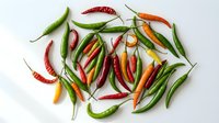 Colorful hot chili peppers collection with red, green, orange and yellow varieties scattered on white background. Fresh spicy ingredients for cooking.