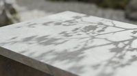 Marble surface with dappled shadow patterns from foliage, suitable for backgrounds, product photography, and design overlays.