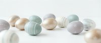 Pastel colored Easter eggs with delicate patterns scattered on white background. Soft mint green, lavender and cream tones create elegant spring holiday decoration.