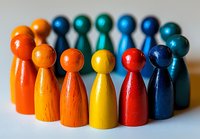 Colorful wooden game pieces arranged in rainbow order forming curved line on white background, representing diversity, teamwork and unity in business concepts.