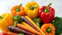 Colorful bell peppers and fresh carrots with broccoli arranged on marble surface for healthy eating, nutrition, cooking, and recipe content.
