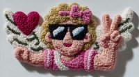 Crocheted hippie girl character with peace sign gesture and heart symbol on white background isolated for craft projects and retro designs.