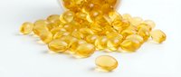 Golden vitamin E capsules spilled from bottle on white background. Omega-3 fish oil supplements for health and wellness nutrition isolated for design use.