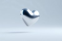 Metallic silver heart floating in soft light against neutral background, creating romantic minimalist composition with shadow beneath. Suitable for valentines designs.